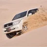 Tourists enjoying dune bashing in Qatar with 4x4 vehicles on golden sand dunes near the Inland Sea.