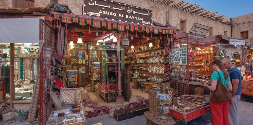 Traditional marketplace in Qatar with tourists shopping for handicrafts, souvenirs, and antiques at Souq Al-Rayyan.
