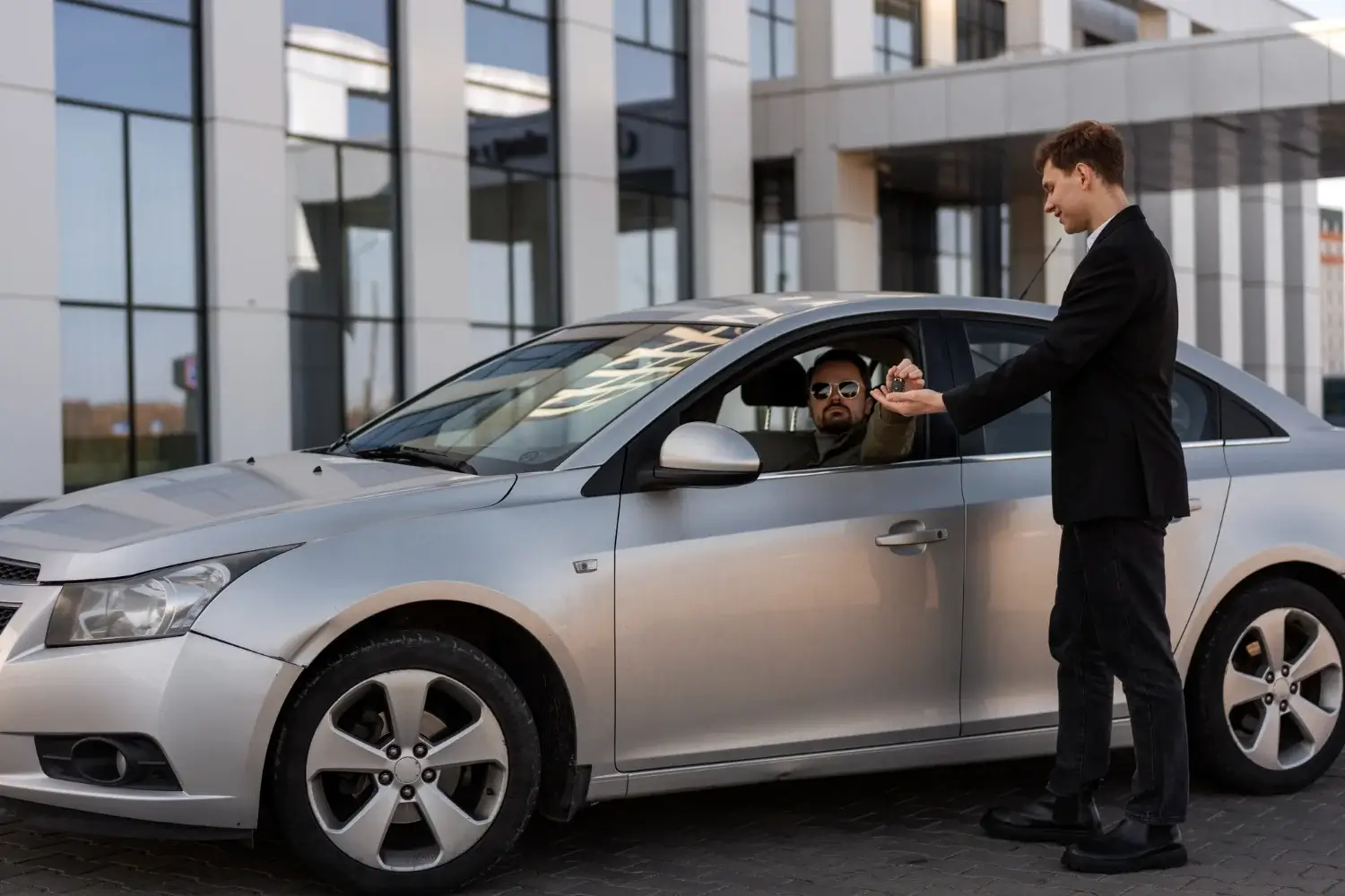 Chauffeur assisting passenger with car service at modern building – Qatar transportation.